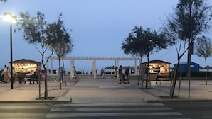 A pedestrian crossing with a white canopy structure, trees, and street lamps. - Francisco Cano bowling (Fuengirola)