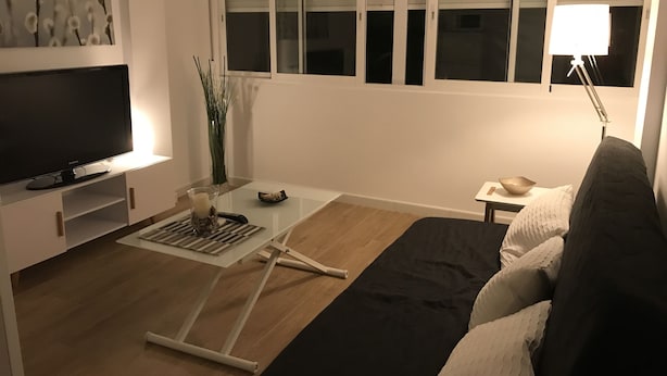 A modern living room with a flat-screen TV, a glass coffee table, a sofa, and a lamp. - Francisco Cano bowling (Fuengirola)