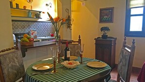 Comedor con mantel a rayas, sillas, un jarrón con flores y una botella de vino.