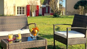 An outdoor seating area with wicker chairs and a table, a glass of orange juice, and a bowl of fruit. - LA CARRETERIE - "Le Philosophe" (cottage 4 pers. 70m2) (Pineuilh)