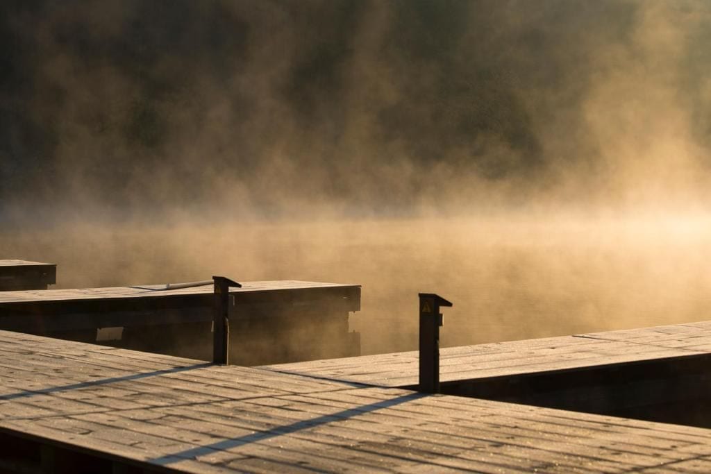 A wooden dock extending into a misty body of water.