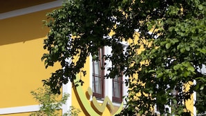 Un edificio amarillo con un gran logotipo de una cara sonriente, plantas en macetas y un letrero que dice