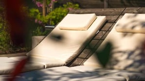 Un área junto a la piscina con sillas de descanso y una valla de madera.