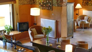 A rustic living room with exposed brick walls, a wooden coffee table, a television, and a comfortable seating area with a sofa and armchairs. - Rural house (full rental) Mas Hortus for 13 peopleOffers (Garriguella)