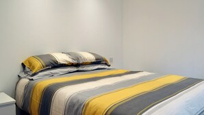 Un lit avec une couvre-lit à rayures dans des tons neutres.