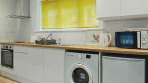 Une cuisine compacte équipée d’un lave-linge, d’un four à micro-ondes et d’un grille-pain.