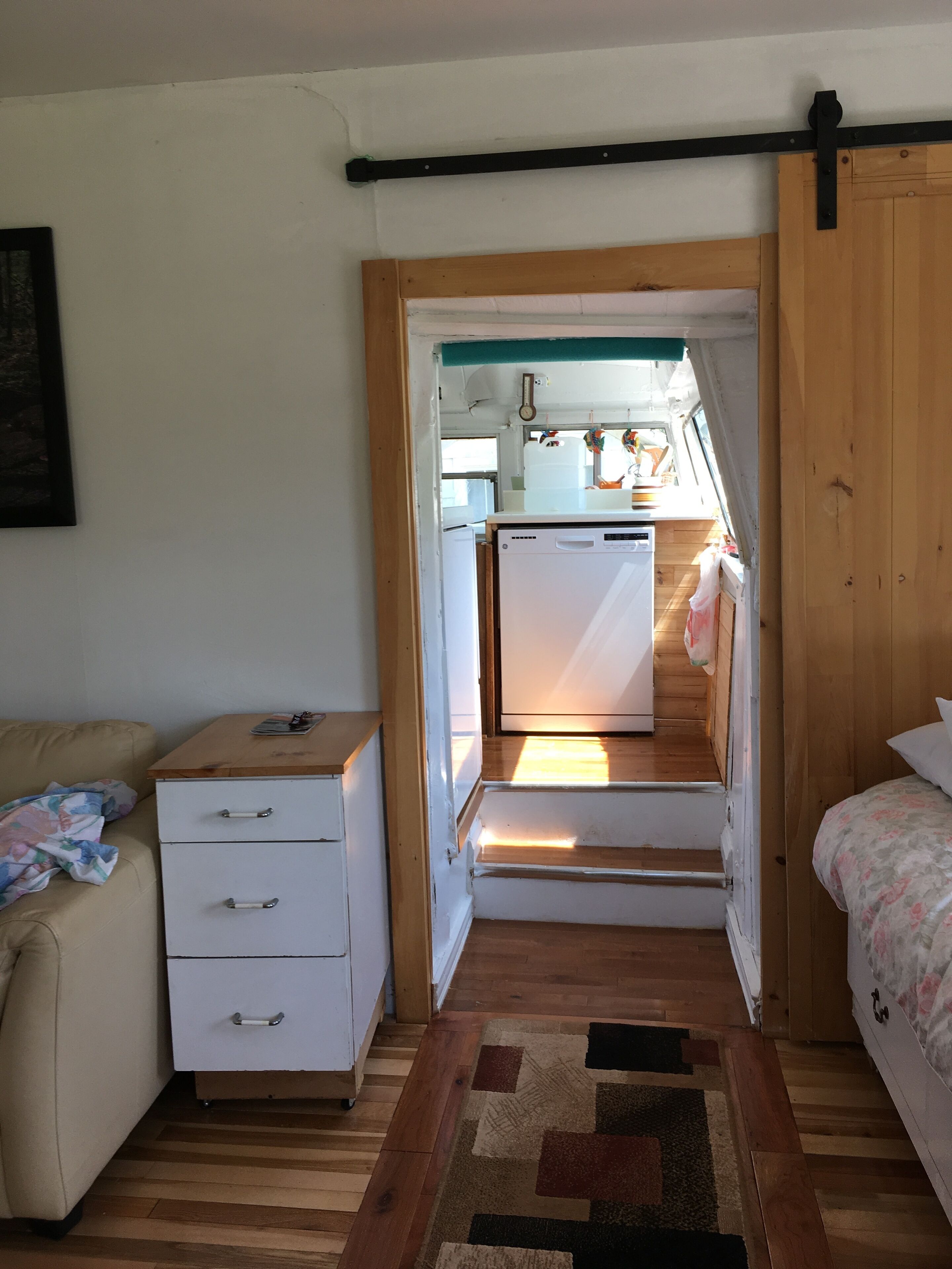A compact room with a kitchenette, a bed, a small desk, and a sofa.
