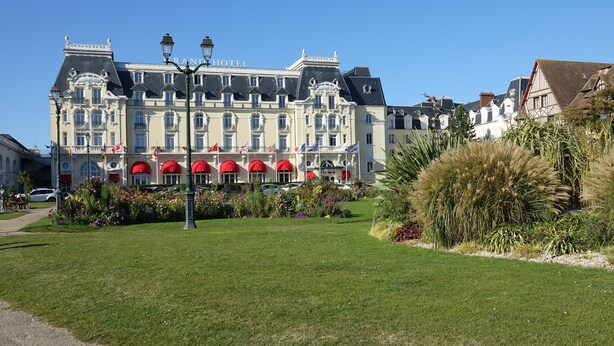 A grand hotel with a classic European architectural style, featuring a prominent entrance with red awnings and a well-maintained garden in the foreground. - Pleasant pied-à-terre on the Côte Fleurie Rated 3 stars by Gîtes de France (Cabourg)