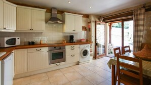 A kitchen with white cabinets, a microwave, a coffee maker, and a washing machine.