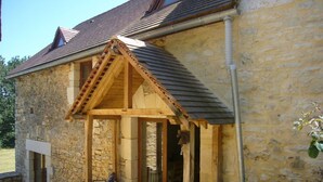 A stone building with a wooden porch and a small window.