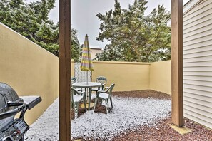 En terrasse med grill, et bord med stole og en parasol.