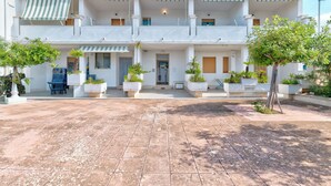 Un hotel de varios pisos con patio, mobiliario exterior y plantas en macetas.