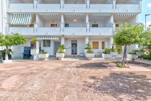 Un hotel de varios pisos con patio, mobiliario exterior y plantas en macetas.
