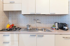 A kitchen with a gas stove, sink, and coffee maker.