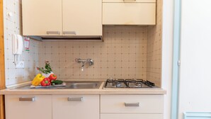 Una cocina con estufa a gas, lavamanos y alacenas.