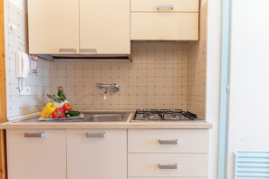 A kitchen with a gas stove, sink, and cabinets.