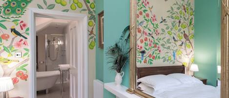 A bedroom with a large mirror, a bed, and a bathroom with a shower and toilet.