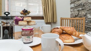 A breakfast setting with pastries, a jar of raspberry conserve, a teapot, and a cup on a wooden table. - 1 bedroom accommodation in Wirksworth, near Matlock (Wirksworth, near Matlock)