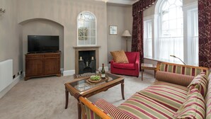 A living room with a television, fireplace, sofa, and a chandelier. - 1 bedroom accommodation in Wirksworth, near Matlock (Wirksworth, near Matlock)