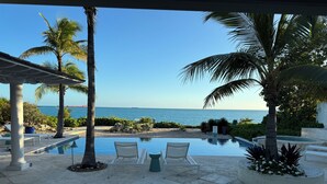 A poolside area with two lounge chairs, a small table, and a view of the ocean.