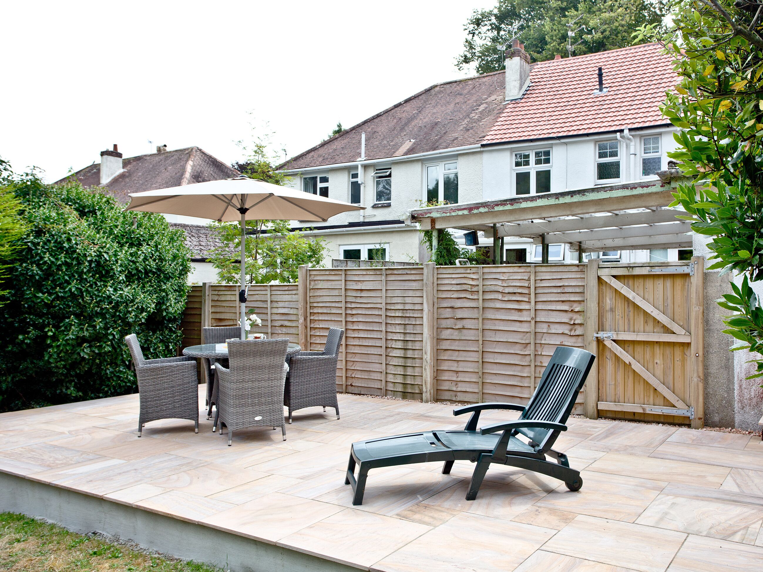 A patio with outdoor furniture, a wooden fence, and a house in the background.
