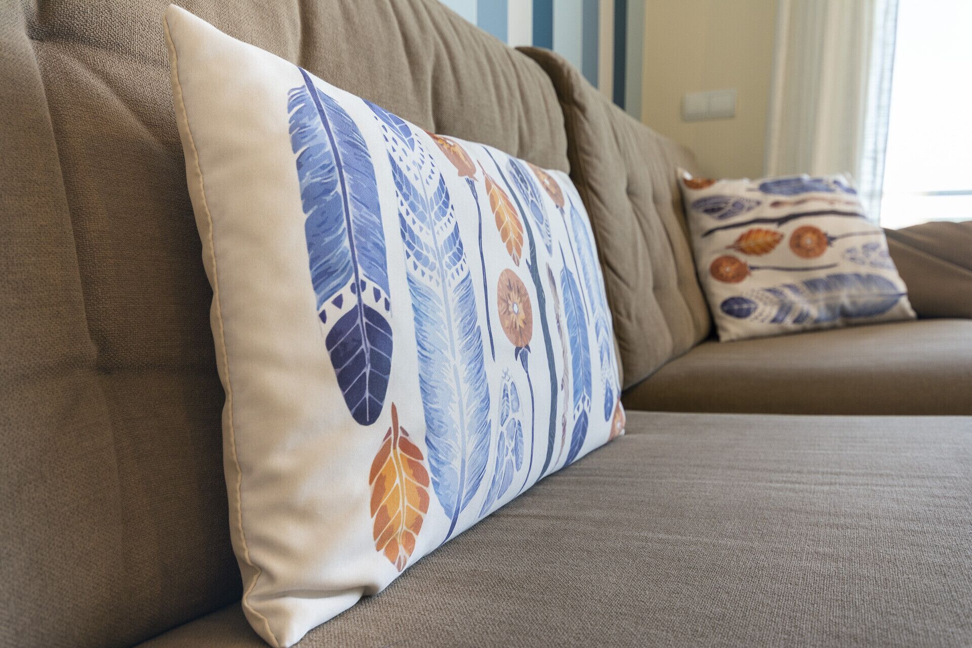 Ein braunes Sofa mit einem dekorativen Kissen mit Blätermotiv.