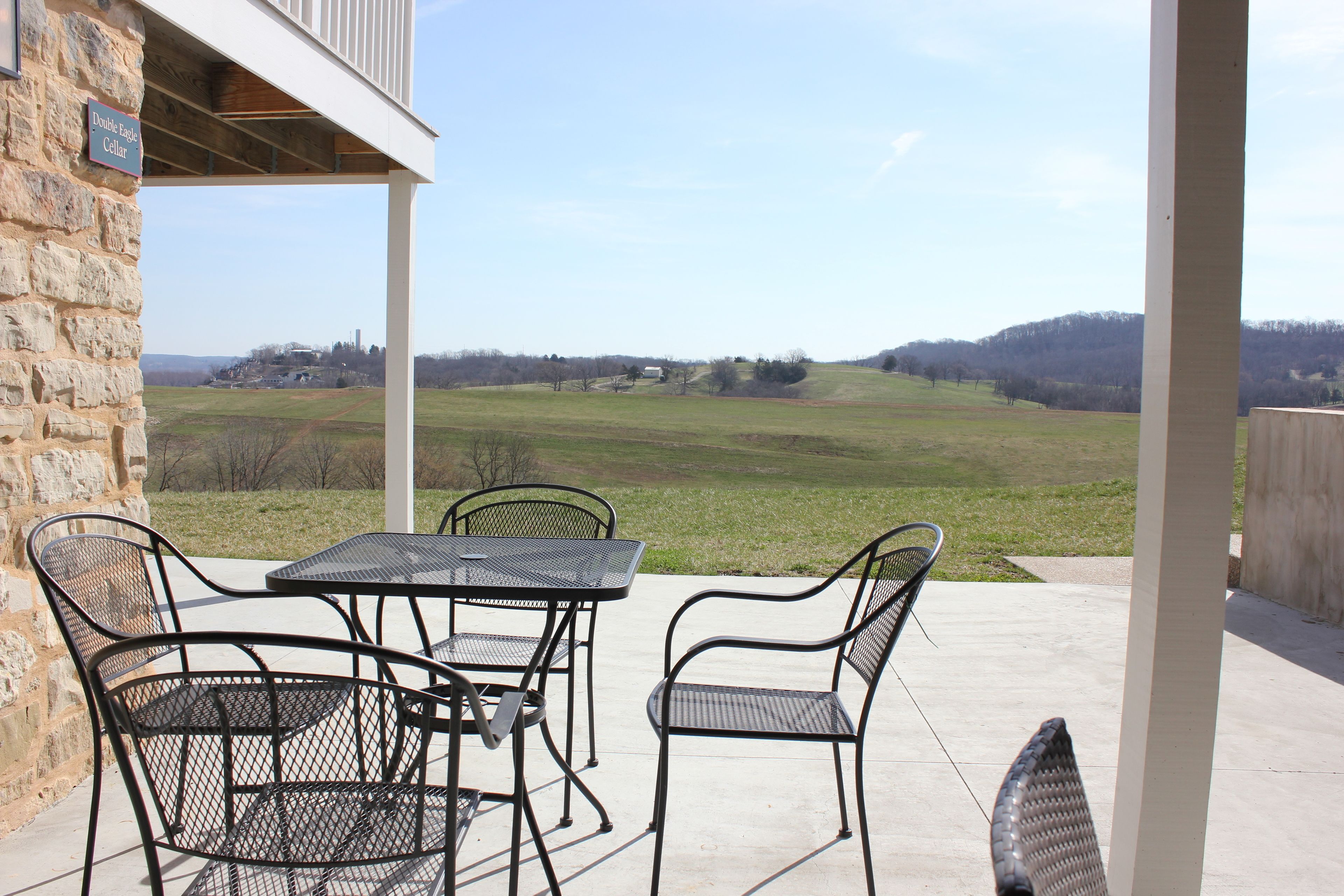 Eine Terrasse mit einer Steinmauer, Metallstühlen und einem Tisch.