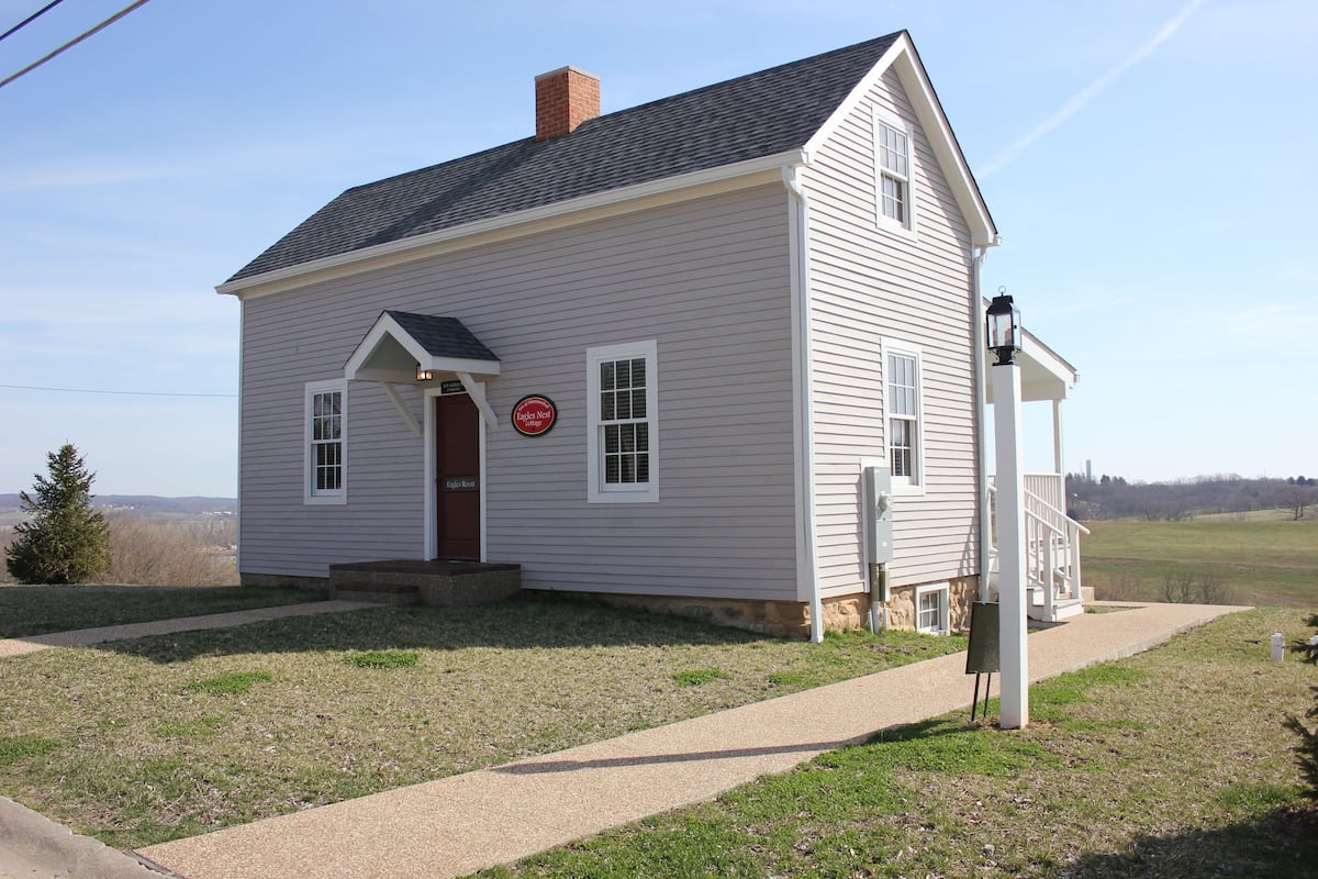 A single-story house with a front porch, a chimney, and a small front yard.