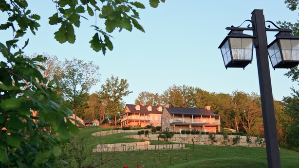 A large house with a stone foundation, a stone wall, and a well-maintained lawn. - Inn at Hermannhof (Hermann)