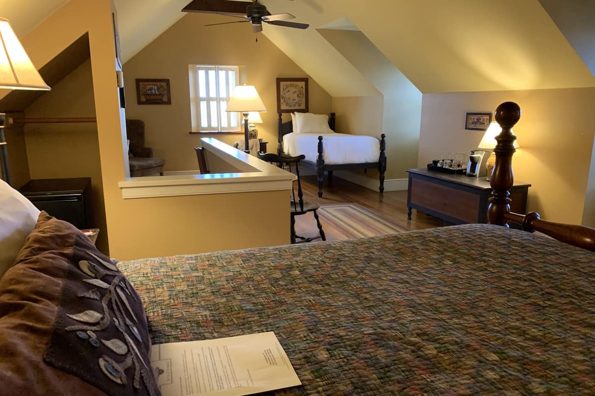 A bedroom with a bed, a desk, a chair, a lamp, and a ceiling fan.
