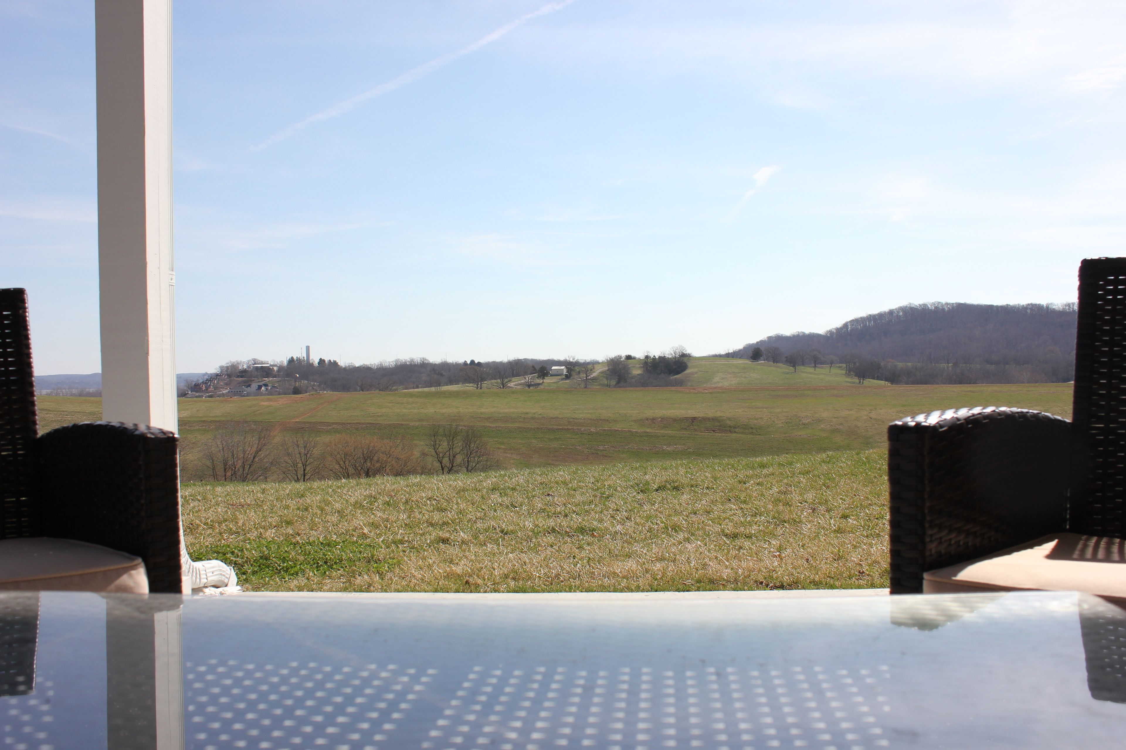 A table with a clear view of a grassy field and distant buildings.