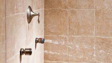 A shower with multiple heads and a handheld showerhead, mounted on a tiled wall.