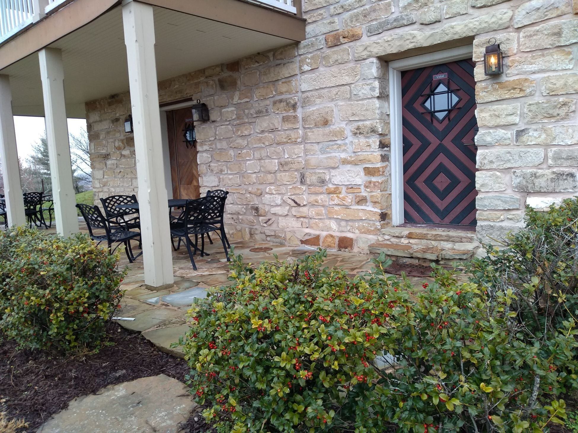 A stone building with a covered patio, outdoor seating, and a decorative door.