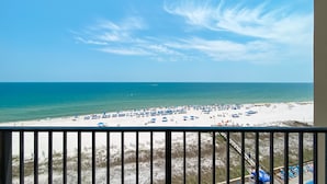 Blick auf einen Sandstrand und das Meer vom Balkon mit Geländer.