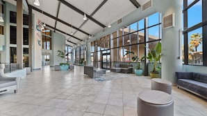 Eine großzügige Lobby mit hoher Decke, großen Fenstern und modernen Sitzbereichen.