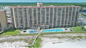 Ein Hochhotel mit mehreren Balkonen, einem Schwimmbad und einer Strandanlage.