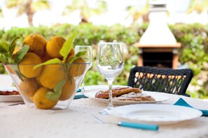 A table with a glass bowl of lemons, a wine glass, and a plate with pastries. - Marina dór IV, house 5, wifi 5 bedrooms, community pool, beach 300m away (Santanyí)