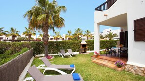 A modern outdoor lounge area with white lounge chairs, a small table, and a barbecue grill. - Marina dór IV, house 5, wifi 5 bedrooms, community pool, beach 300m away (Santanyí)
