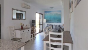 A spacious living area with a dining table, chairs, a TV, and a large window. - Marina dór IV, house 5, wifi 5 bedrooms, community pool, beach 300m away (Santanyí)