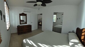 A bedroom with a large bed, a ceiling fan, a dresser, and a mirror. - High End Amenities, Panoramic Sunset View, Roof Top Deck (Aguada)