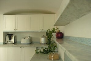 A kitchen with white cabinets, a toaster, a blender, a plant, and a loaf of bread on the counter. - Loft in San Lorenzo, two minutes from the aquarium; with parking possibility (Genova, Liguria)