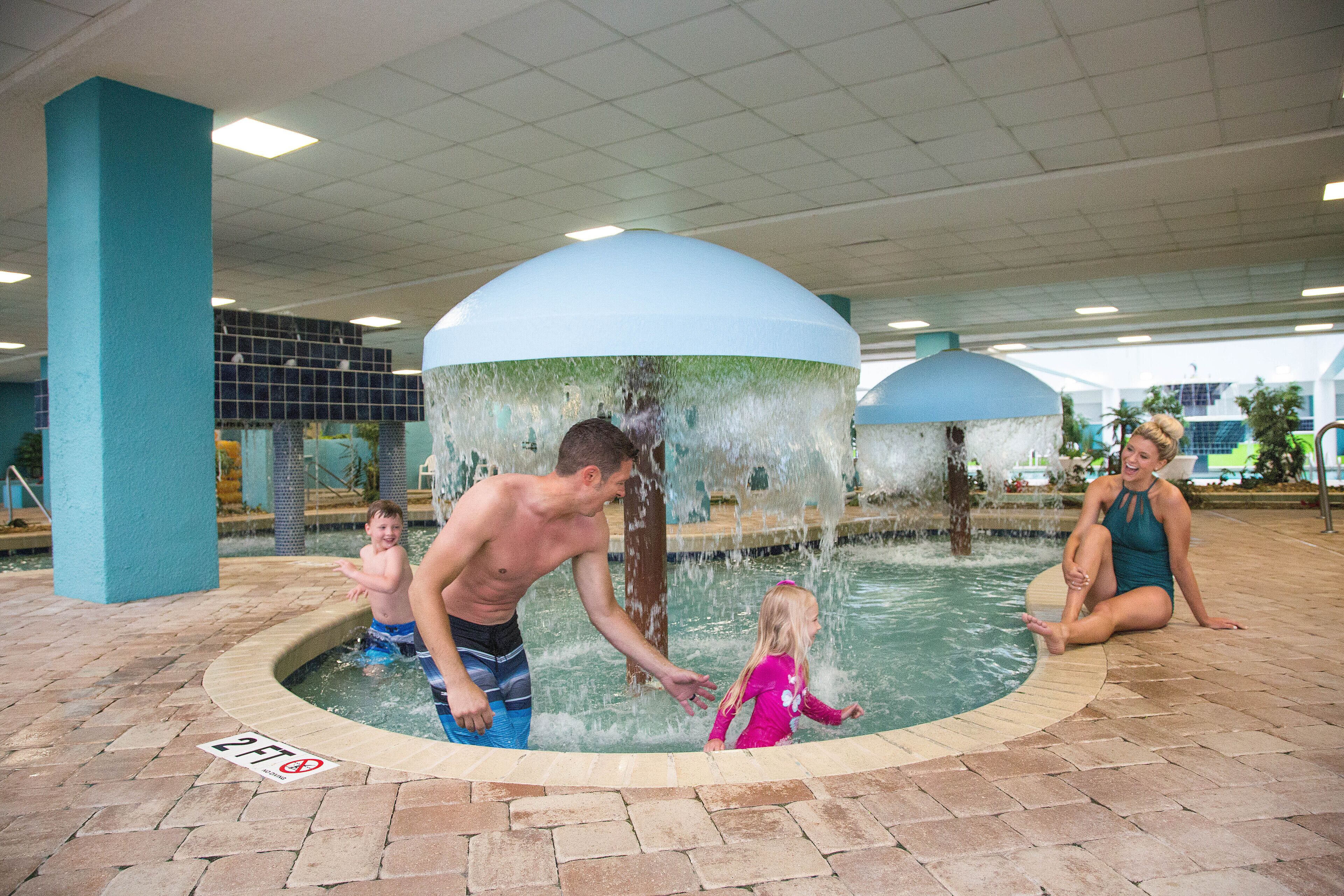 A pool area with a water feature, a tiled floor, and a sign indicating a depth of 2 feet.