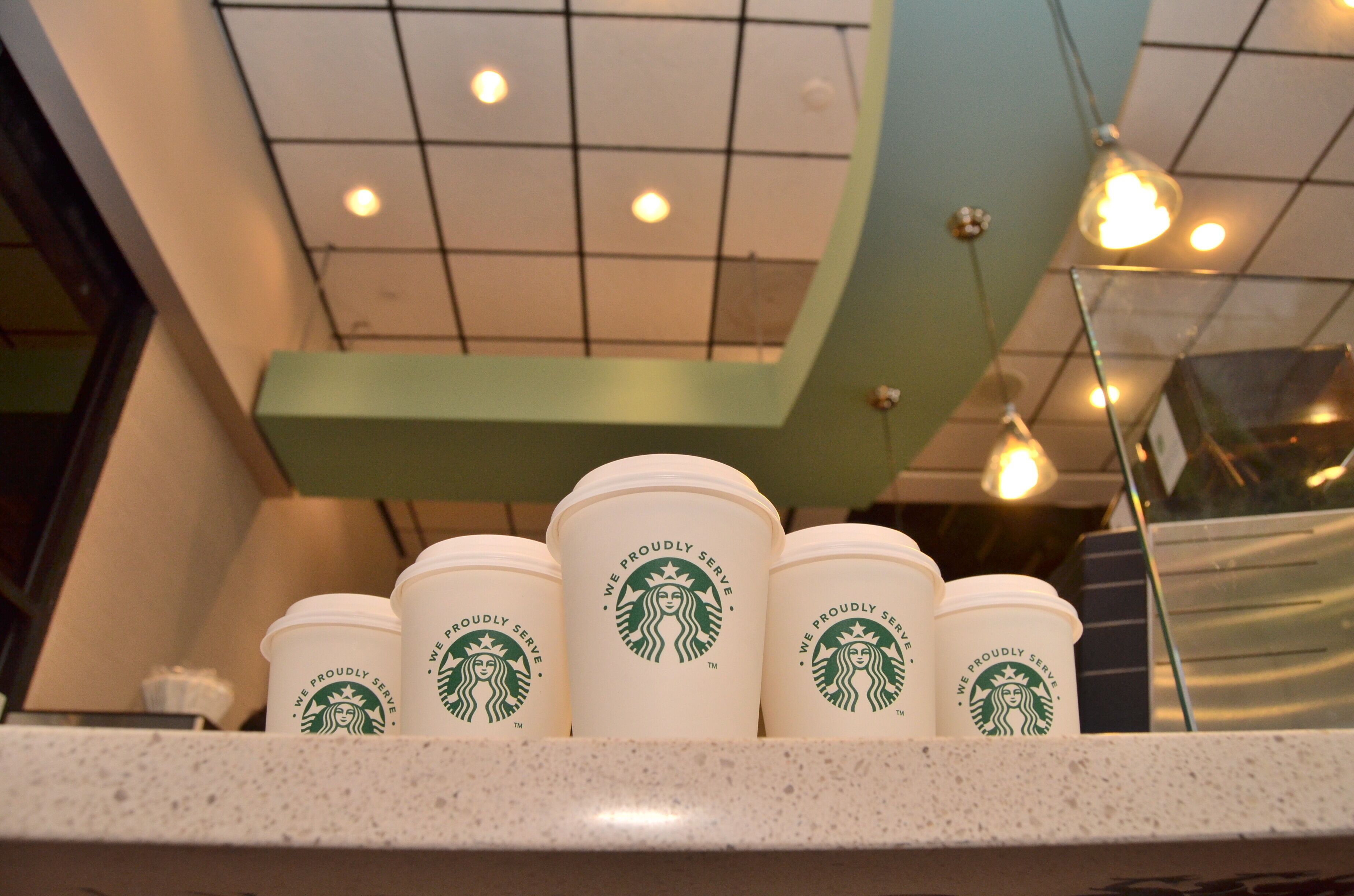 A Starbucks display with multiple cups and a green ceiling.