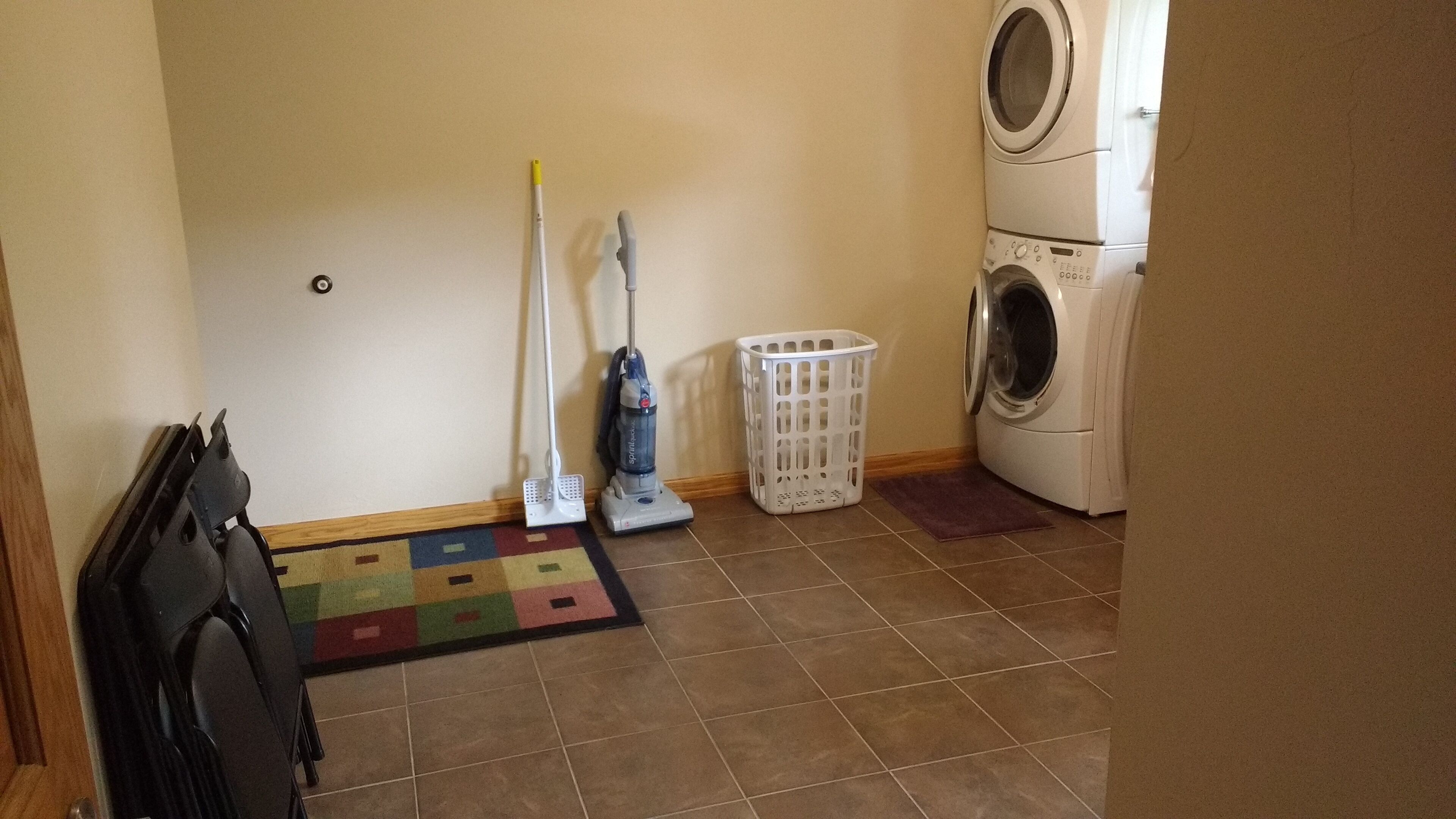 Une buanderie équipée d’un lave-linge, d’un aspirateur et d’un panier à linge.
