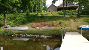 Une propriété au bord du lac, dotée d’un quai, d’un petit bateau et d’un espace salon extérieur.