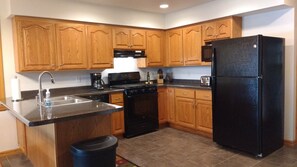 Fully equipped kitchen with a stainless steel sink, coffee maker, stove, and refrigerator.