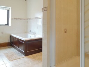 Une salle de bain avec une grande baignoire, un lavabo et un espace douche.