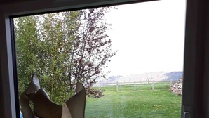 Ein Zimmer mit großem Fenster, Holzboden und einer Skulptur an der Fensterbank.