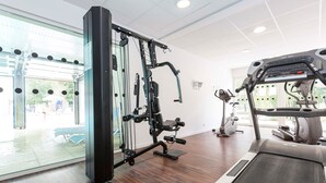 A gym with a treadmill, weight machines, and a large window. - Studio cosy et charmant 2p (Hourtin)