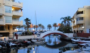 Un puerto deportivo con barcos amarrados, un puente y palmeras.